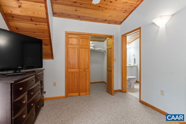 bedroom featuring baseboards, light carpet, wood ceiling, and a walk in closet