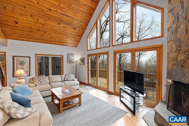 living room with light wood finished floors, a stone fireplace, wood ceiling, and high vaulted ceiling