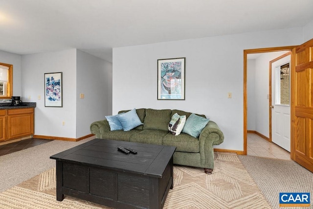 living area featuring light colored carpet, light tile patterned floors, and baseboards