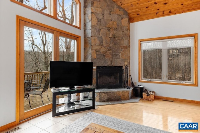 living area with visible vents, baseboards, lofted ceiling, and a stone fireplace