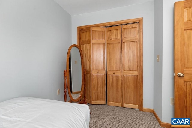 carpeted bedroom featuring a closet and baseboards