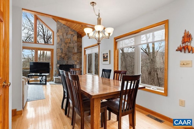 dining area featuring lofted ceiling, light wood-type flooring, an inviting chandelier, and visible vents