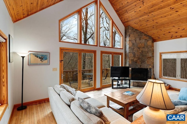 living room featuring hardwood / wood-style flooring, vaulted ceiling, wood ceiling, baseboards, and a stone fireplace