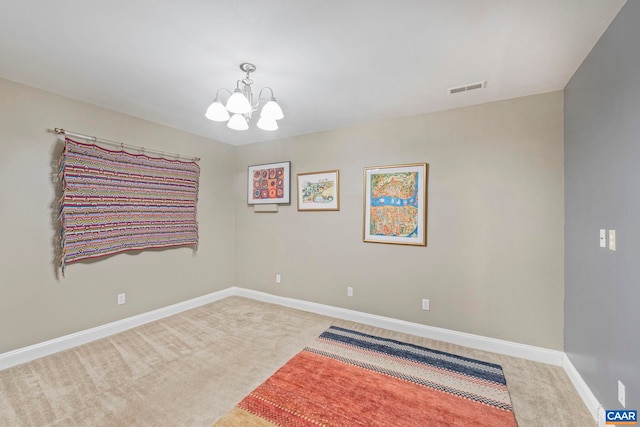 spare room with baseboards, a notable chandelier, visible vents, and carpet floors