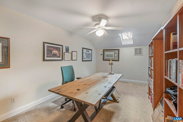home office with light colored carpet, baseboards, lofted ceiling with skylight, and ceiling fan