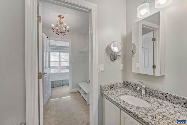 bathroom featuring baseboards, vanity, and a notable chandelier