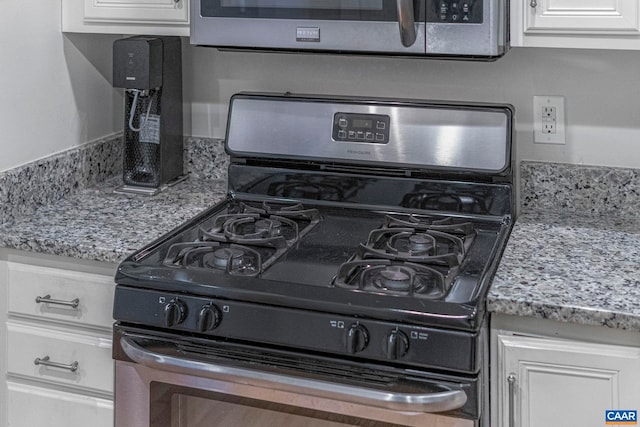 room details with stainless steel gas range and white cabinetry