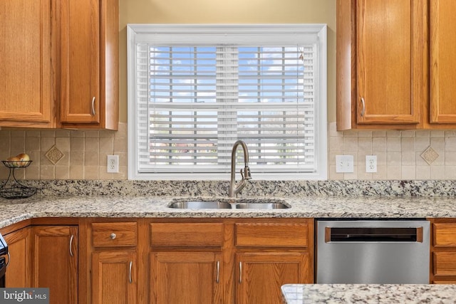 kitchen with stainless steel dishwasher, a sink, plenty of natural light, and brown cabinets