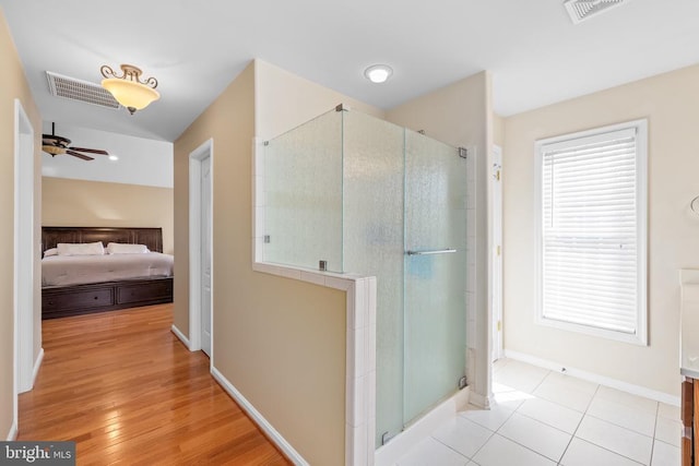 ensuite bathroom with a shower with door, ceiling fan, and baseboards