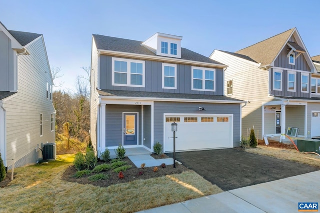 traditional home featuring central AC, board and batten siding, aphalt driveway, and an attached garage