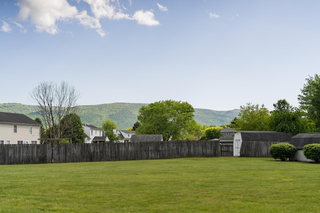 view of yard featuring a shed, a mountain view, and an outbuilding