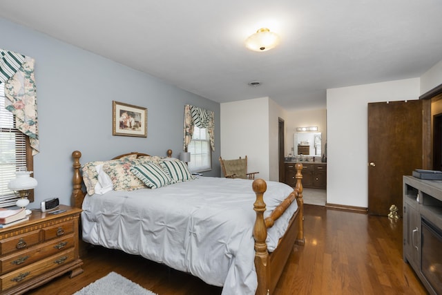 bedroom with dark wood-style floors and ensuite bath