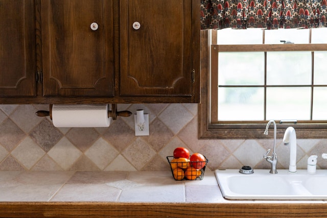 kitchen with a sink, dark brown cabinets, light countertops, and tasteful backsplash
