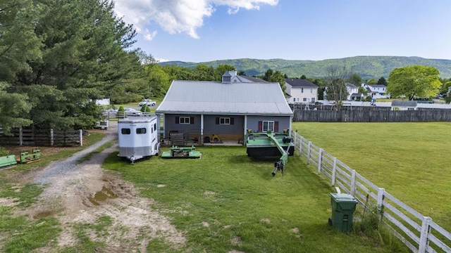 back of house with a mountain view, metal roof, and driveway
