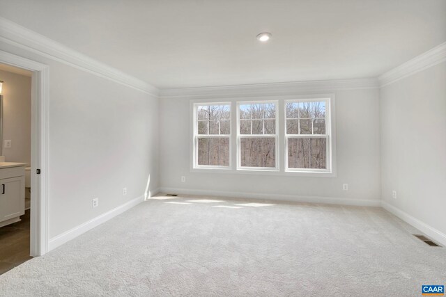 spare room featuring carpet flooring, ornamental molding, and baseboards
