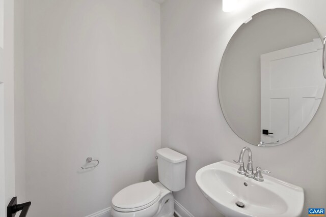 bathroom featuring a sink, baseboards, and toilet