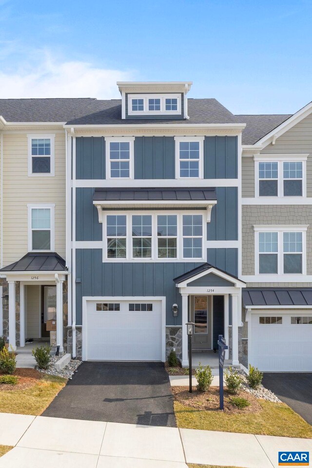 townhome / multi-family property featuring stone siding, board and batten siding, roof with shingles, driveway, and a standing seam roof