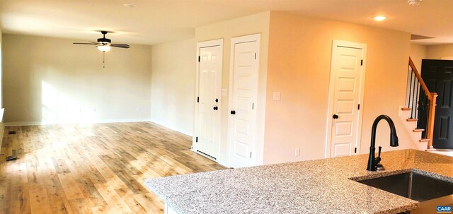 kitchen featuring ceiling fan, sink, light stone counters, and light hardwood / wood-style floors