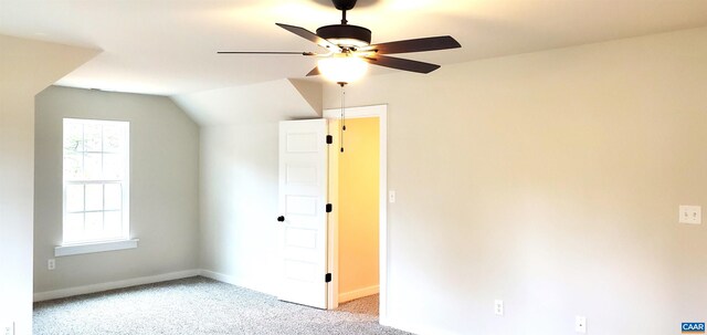 interior space with ceiling fan, vaulted ceiling, and light carpet