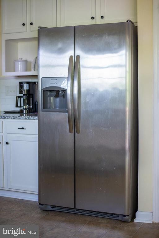 kitchen featuring stainless steel fridge with ice dispenser, white cabinetry, light stone counters, and open shelves