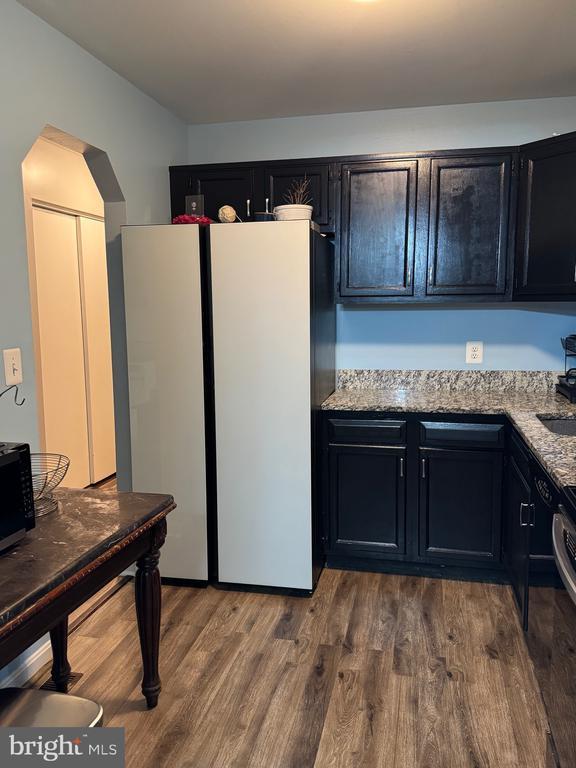 800 Dunlap St, Fredericksburg, VA 22407 - kitchen featuring freestanding refrigerator, light stone counters, black microwave, and dark wood-style floors