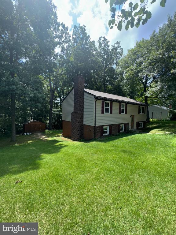 800 Dunlap St, Fredericksburg, VA 22407 - view of home's exterior featuring a chimney, a lawn, and view of wooded area