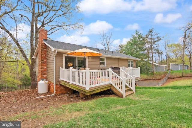  - back of property with a chimney, a deck, a yard, and roof with shingles