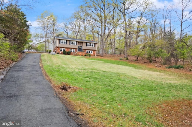  - raised ranch featuring a front yard, brick siding, and asphalt driveway
