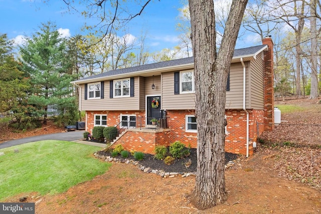  - bi-level home with brick siding, a chimney, and a front lawn