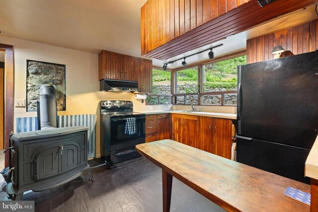 115 Oventop Mountain Ln, Sperryville, VA 22740 - kitchen with black appliances, under cabinet range hood, a wood stove, butcher block counters, and brown cabinetry