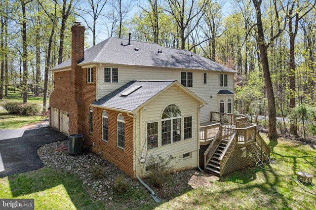  - back of property featuring a chimney, stairs, driveway, a garage, and a deck