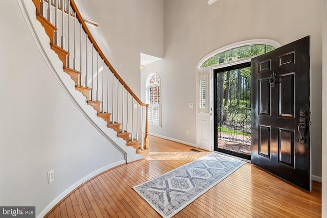  - foyer entrance with hardwood / wood-style flooring, a towering ceiling, stairs, and baseboards