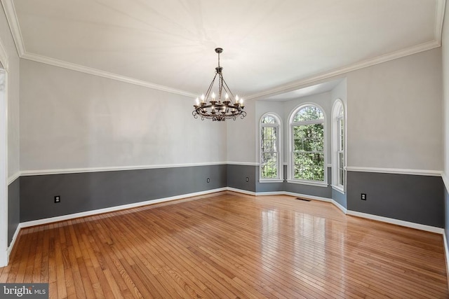  - unfurnished room with a chandelier, hardwood / wood-style flooring, baseboards, and crown molding