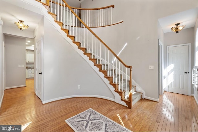  - foyer with light wood finished floors, baseboards, and stairway