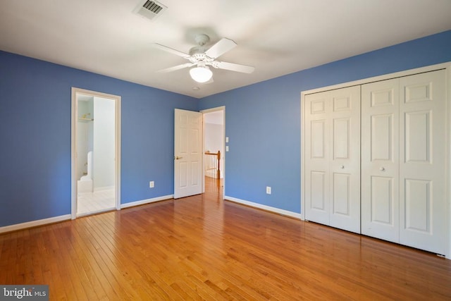  - unfurnished bedroom featuring baseboards, light wood-type flooring, a closet, a ceiling fan, and ensuite bath