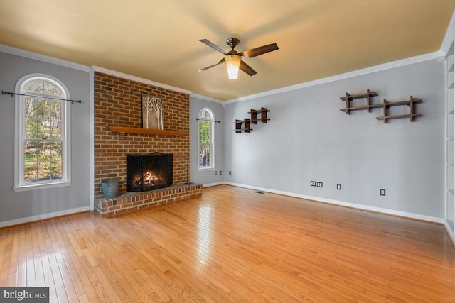  - unfurnished living room with hardwood / wood-style floors, ceiling fan, a brick fireplace, baseboards, and crown molding