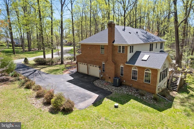  - view of side of home with roof with shingles, a chimney, an attached garage, asphalt driveway, and brick siding
