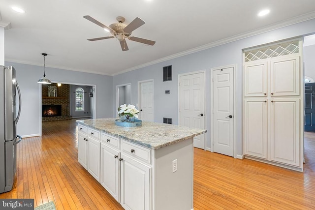  - kitchen with freestanding refrigerator, a ceiling fan, light wood finished floors, white cabinets, and a center island