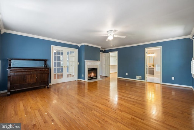  - unfurnished living room with french doors, light wood-style flooring, ceiling fan, baseboards, and crown molding