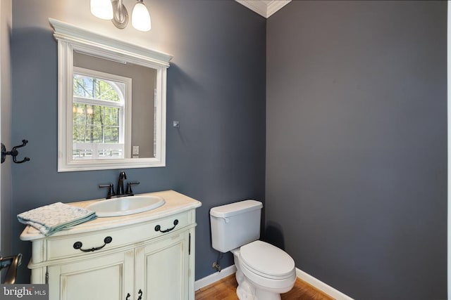  - half bath with toilet, vanity, wood finished floors, ornamental molding, and baseboards