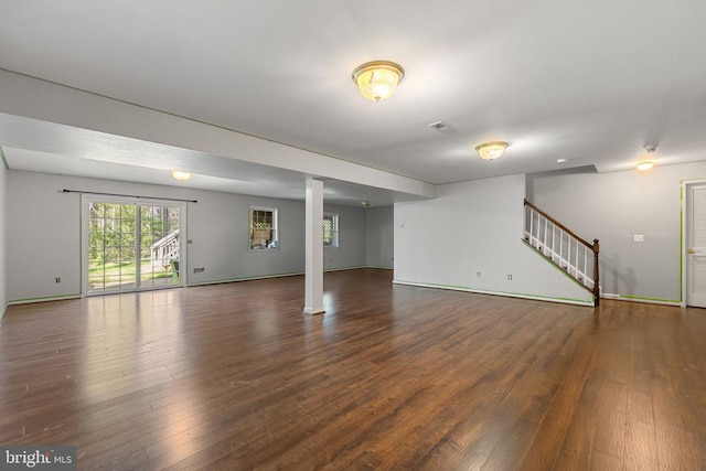  - unfurnished living room featuring wood finished floors, baseboards, stairs, and decorative columns