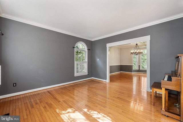  - empty room featuring a chandelier, light wood-style floors, plenty of natural light, ornamental molding, and baseboards