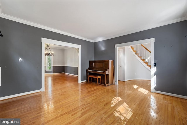  - unfurnished living room featuring light wood finished floors, a chandelier, stairway, baseboards, and ornamental molding