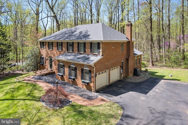  - view of front facade featuring a chimney, asphalt driveway, a shingled roof, a garage, and central air condition unit