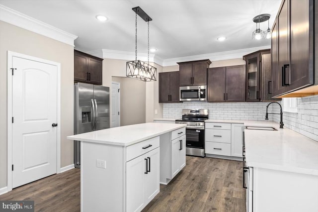 12521 Wilderness Park Dr, Spotsylvania, VA 22551 - kitchen featuring appliances with stainless steel finishes, ornamental molding, dark brown cabinetry, a center island, and backsplash
