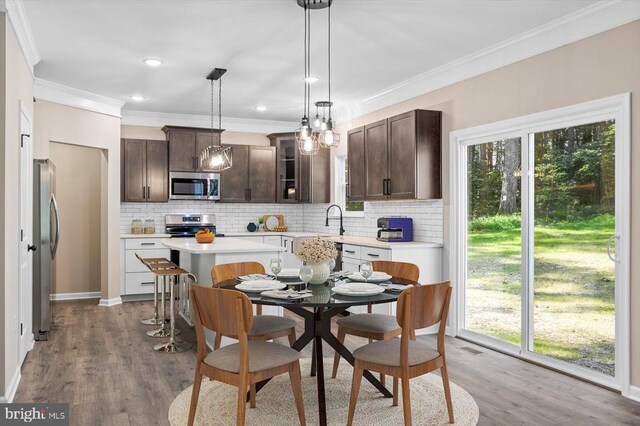 12521 Wilderness Park Dr, Spotsylvania, VA 22551 - kitchen with stainless steel appliances, dark brown cabinets, decorative backsplash, light countertops, and ornamental molding
