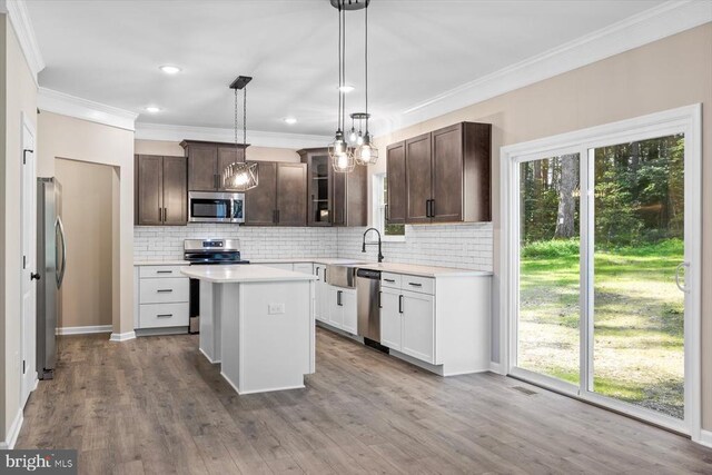12521 Wilderness Park Dr, Spotsylvania, VA 22551 - kitchen featuring appliances with stainless steel finishes, decorative backsplash, dark brown cabinetry, a kitchen island, and crown molding