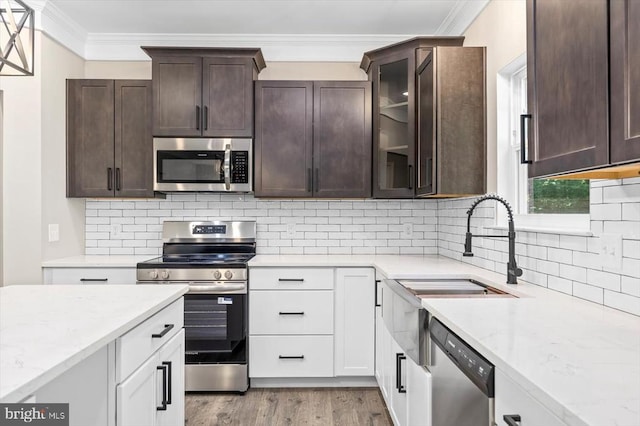 12521 Wilderness Park Dr, Spotsylvania, VA 22551 - kitchen with stainless steel appliances, ornamental molding, dark brown cabinets, light stone counters, and white cabinetry