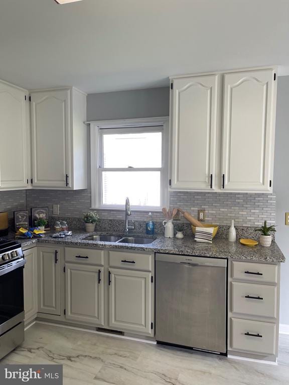 4209 Oakhill Rd, Fredericksburg, VA 22408 - kitchen featuring stainless steel appliances, light marble finish floors, dark stone countertops, and white cabinetry