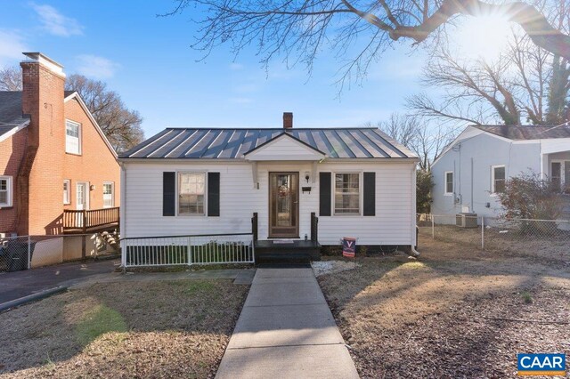 bungalow-style house featuring a chimney, metal roof, central air condition unit, fence private yard, and a standing seam roof